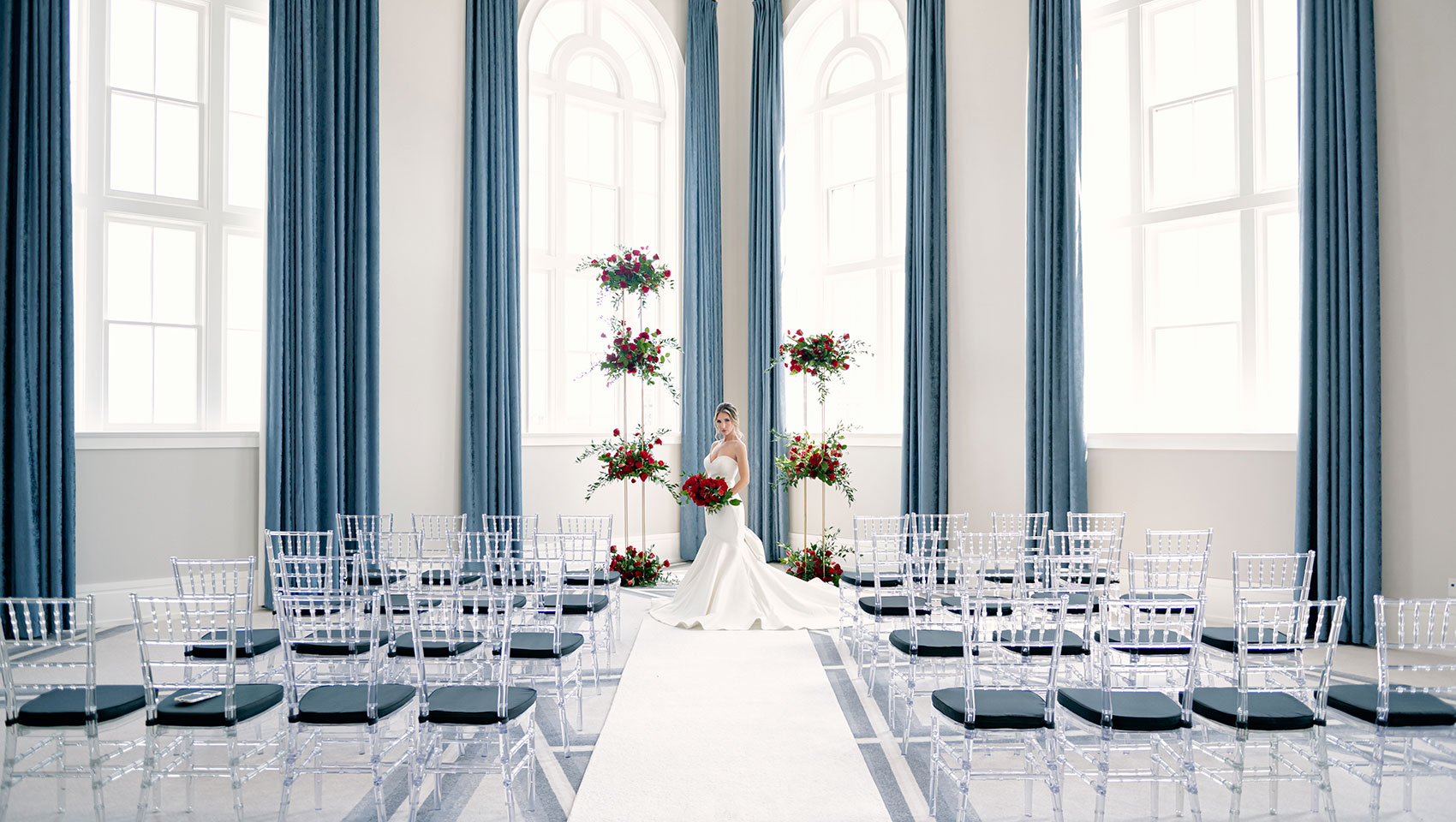 ballroom set up for a wedding with chairs and a bride standing at altar