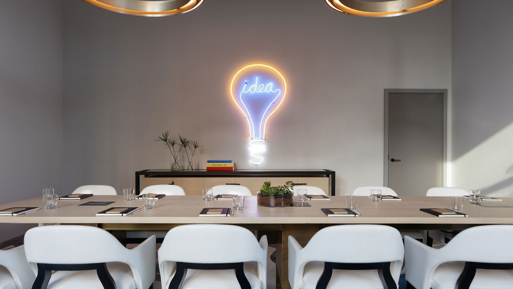 Meeting room setup with lightbulb neon light on wall