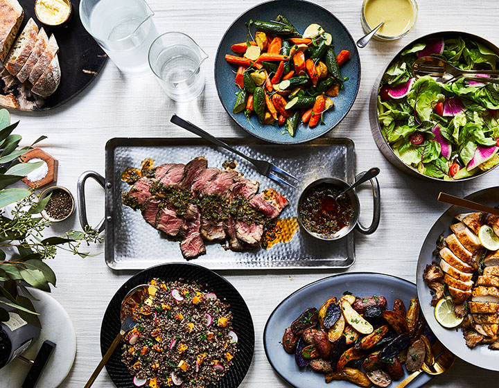 Spread of various salads, steak plates, and vegetables